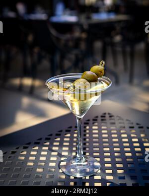Piermont, NY - US - 20 août 2023 image verticale d'un martini sale, garni de trois olives, servi directement, avec une faible profondeur de champ. Banque D'Images