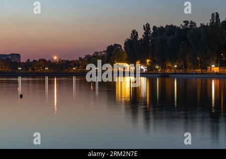 Beau coucher de soleil et réflexion de lumières sur un lac dans un parc public à Chisinau, Moldavie Banque D'Images