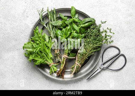 Assiette avec herbes fraîches et ciseaux sur fond clair Banque D'Images