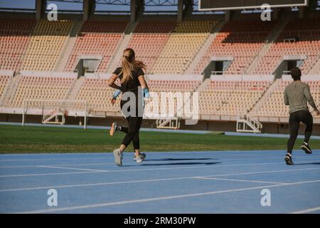 Des amis masculins et féminins s'entraînent ensemble au stade. Ils courent Banque D'Images