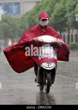 Bildnummer: 59933343  Datum: 02.07.2013  Copyright: imago/Xinhua (130702) -- NANNING, July 2, 2013 (Xinhua) -- A citizen rides in the rain on a road in Nanning City, capital of south China s Guangxi Zhuang Autonomous Region, July 2, 2013. Rumbia, the sixth tropical storm to hit China this year, landed in the city of Zhanjiang of Guangdong Province at 5:30 a.m. Tuesday and has entered neighboring Guangxi on Tuesday. The local meteorological center has issued a yellow storm alert. (Xinhua/Lu Bo an) (zwx) CHINA-GUANGXI-TROPICAL STORM RUMBIA(CN) PUBLICATIONxNOTxINxCHN Gesellschaft Verkehr Strasse Stock Photo