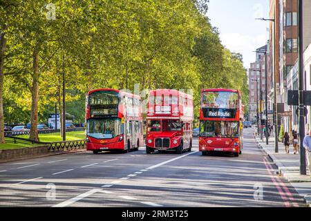 Trois générations de bus rouges londoniens circulant à Mayfair près de Hyde Park Banque D'Images