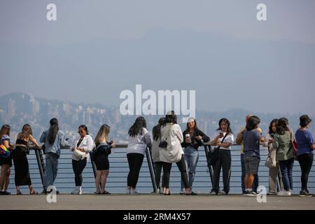 Vancouver, Canada. 26 août 2023. Les gens se rassemblent sur le front de mer dans la brume au centre-ville de Vancouver, Colombie-Britannique, Canada, 26 août 2023. Samedi, le Grand Vancouver a poursuivi un avis sur la qualité de l'air pour la région métropolitaine de Vancouver en raison de la forte concentration de particules fines causée par la fumée des feux de forêt qui se propagent à travers la Colombie-Britannique. Crédit : Liang Sen/Xinhua/Alamy Live News Banque D'Images