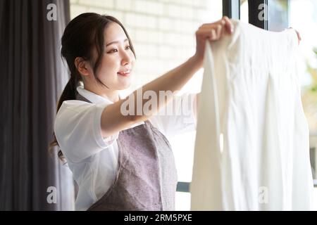 Femme asiatique accrochant le linge par la fenêtre Banque D'Images