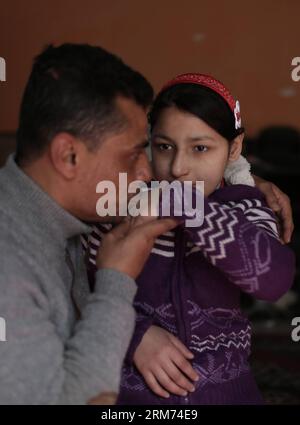 (140213) -- GAZA, 13 février 2014 (Xinhua) -- Une jeune palestinienne de 12 ans, Rula Ali (R), qui souffre d'une laryngite chronique, est embrassée par un de ses proches à sa maison dans le camp de réfugiés de Nuseirat, au centre de la bande de Gaza, le 13 février 2014. Plusieurs patients palestiniens comme Rula qui cherchent à se faire soigner en Israël se sont vu refuser l'accès par les autorités israéliennes via le point de passage d'Erez avec Gaza pour détenir des documents utilisant le terme État de Palestine . (Xinhua/Wissam Nassar) MIDEAST-GAZA-PATIENTS REFUSÉ PAR ISRAËL PUBLICATIONxNOTxINxCHN Gaza février 13 2014 XINHUA une fille PALESTINIENNE de 12 ans Ali r Who suf Banque D'Images