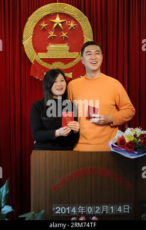 (140214) -- HANGZHOU, 14 février 2014 (Xinhua) -- les jeunes mariés tenant leur certificat de mariage posent pour des photos dans un registre de mariage le jour de la Saint-Valentin ainsi que lors du Festival des lanternes traditionnelles chinoises à Hangzhou, capitale de la province du Zhejiang de l'est de la Chine, le 14 février 2014. De nombreux jeunes mariés ont choisi d'obtenir des licences de mariage le jour de la Saint-Valentin cette année, car il coïncide avec le Festival des lanternes, le 15e jour du premier mois du calendrier lunaire chinois. (Xinhua/Ju Huanzong) (lfj) CHINA-VALENTINE S DAY-MARRIAGE REGISTRATION (CN) PUBLICATIONxNOTxINxCHN Hangzhou février 14 2014 XINHUA Newlyw Banque D'Images