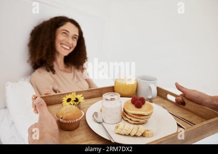 Petit déjeuner, romance et femme au lit pour surprise, célébration d'anniversaire et anniversaire spécial. Matin, amour et couple heureux avec de la nourriture, crêpes et Banque D'Images