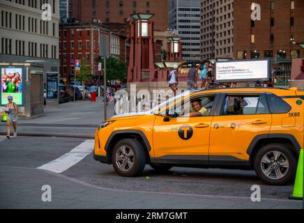 Manhattan New York, NY, USA, 08-13-2023 taxi jaune arrêté à l'intersection avec des gratte-ciel et des piétons. Le conducteur sourit à la caméra et fait une peac Banque D'Images