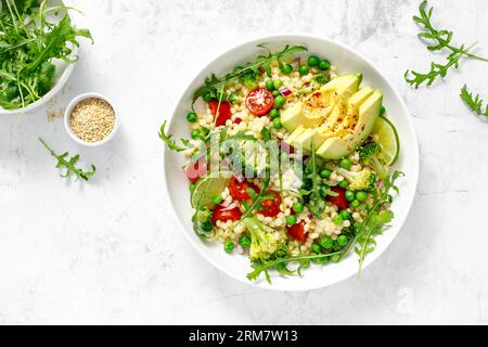 Salade de couscous avec brocoli, pois verts, tomates, avocat et roquette fraîche. Nourriture végétarienne saine à base de plantes naturelles pour le déjeuner, cuisine israélienne, Banque D'Images