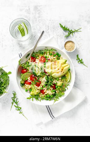 Salade de couscous avec brocoli, pois verts, tomates, avocat et roquette fraîche. Nourriture végétarienne saine à base de plantes naturelles pour le déjeuner, cuisine israélienne, Banque D'Images