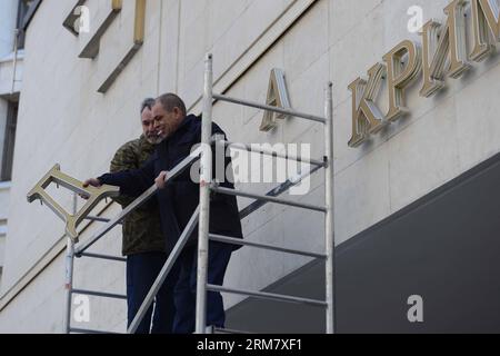 (140318) -- SIMFEROPOL, 18 mars 2014 (Xinhua) -- des travailleurs démontent les panneaux ukrainiens sur le Parlement de Crimée à Simferopol, République de Crimée, le 18 mars 2014. Le président russe Vladimir Poutine et les dirigeants de Crimée ont signé mardi un traité acceptant la République de Crimée et la ville de Sébastopol comme faisant partie du territoire russe. (Xinhua/Sadate) (cru) CRIMÉE-SIMFEROPOL-RUSSIE-TRAITÉ PUBLICATIONxNOTxINxCHN Simferopol Mars 18 2014 les travailleurs DE XINHUA démantelent les panneaux ukrainiens SUR LE Parlement à Simferopol la République de Crimée Mars 18 2014 le Président russe Vladimir Banque D'Images