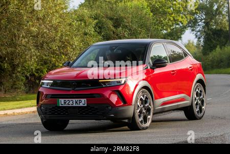 Whittlebury,Northants,UK -Aug 26th 2023 : 2023 rouge Vauxhall Mokka voiture électrique voyageant sur une route de campagne anglaise Banque D'Images