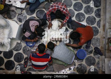 (140325) -- VARANASI, 25 mars 2014 (Xinhua) -- des artisans travaillent sur une sculpture en pierre dans une usine de Varanasi, une vieille ville sainte hindoue située sur la rive du Gange, en Inde, le 25 mars 2014. L'industrie de la sculpture sur pierre de Varanasi, ville sainte riveraine, est en plein essor. Les artistes des États environnants produisent non seulement des sculptures de dieux et de déesses, mais aussi des humains. Les sculptures en pierre de Varanasi, étant fantaisie dans le style et le design, attirent de plus en plus de clients chaque année et ils sont vendus à travers l'Inde et les marchés étrangers. (Xinhua/Zheng Huansong) INDE-VARANASI-SCULPTURE SUR PIERRE PUBL Banque D'Images