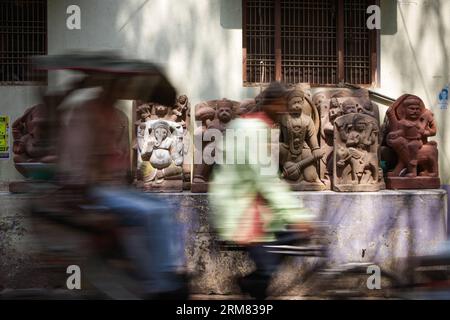 (140325) -- VARANASI, 25 mars 2014 (Xinhua) -- Un tireur de pousse-pousse transporte un passager qui traverse des sculptures en pierre à l'extérieur d'une usine à Varanasi, une vieille ville sainte hindoue située sur la rive du Gange, en Inde, le 25 mars 2014. L'industrie de la sculpture sur pierre de Varanasi, ville sainte riveraine, est en plein essor. Les artistes des États environnants produisent non seulement des sculptures de dieux et de déesses, mais aussi des humains. Les sculptures en pierre de Varanasi, étant fantaisie dans le style et le design, attirent de plus en plus de clients chaque année et ils sont vendus à travers l'Inde et les marchés étrangers. (Xinhua/Zheng Huansong Banque D'Images