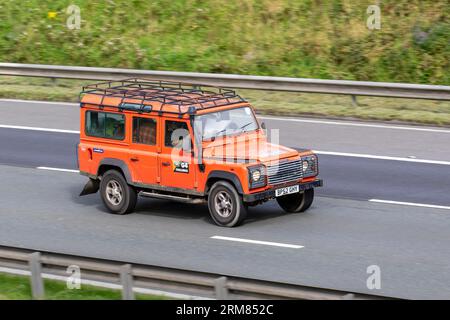 2003 Land Rover Defender 110 Td5 County Orange LCV Station Wagon Diesel 2495 cc se déplaçant à grande vitesse sur l'autoroute M6 dans le Grand Manchester, Royaume-Uni Banque D'Images