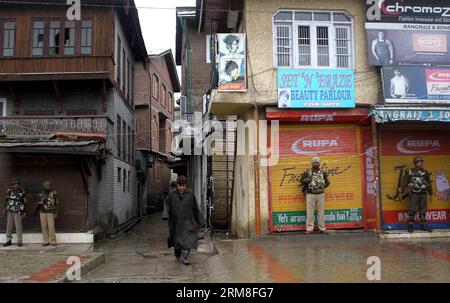 Un Cachemire passe devant des soldats paramilitaires indiens dans un marché fermé lors d’une grève à Srinagar, la capitale estivale du Cachemire contrôlé par l’Inde, le 12 avril 2014. Un appel à la grève lancé samedi par l'alliance séparatiste a frappé la vie normale dans les zones à majorité musulmane du Cachemire contrôlé par l'Inde, y compris la capitale estivale de la région, Srinagar. (Xinhua/Javed Dar) KASHMIR-SRINAGAR-STRIKE PUBLICATIONxNOTxINxCHN un homme cachemirien passe devant des soldats paramilitaires indiens dans un marché fermé lors d'une grève à Srinagar, capitale d'été du Cachemire contrôlé par l'Inde avril 12 2014 un appel à la grève lancé par le séparatiste Allianc Banque D'Images