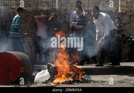 Les Juifs ultra-orthodoxes brûlent de la nourriture contenant des céréales levées à Modi en élite, avant le début de la fête de la Pâque, le 14 avril 2014. La Pâque est une importante fête juive dérivée de la Bible. Le peuple juif célèbre la Pâque comme une commémoration de sa libération il y a plus de 3 300 ans par Dieu de l'esclavage dans l'Egypte ancienne qui était gouvernée par les Pharaons, et de sa liberté en tant que nation sous la direction de Moïse. Pendant la Pâque, manger du chametz, c'est-à-dire du pain et d'autres aliments faits avec du grain levé, est interdit selon la loi religieuse juive. (Xinhua/Gil Cohen Magen) Banque D'Images