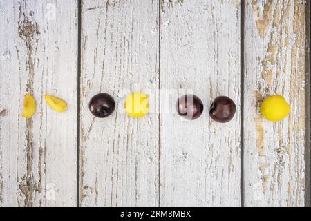 Une rangée de prunes rouges et jaunes mûres sur une table en planche blanche Banque D'Images