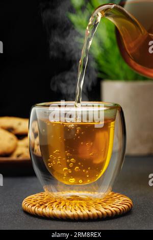 thé chaud coulant de théière dans une tasse en verre sur la table Banque D'Images