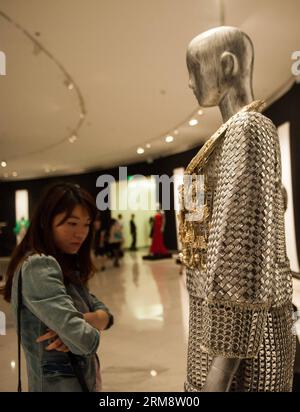 (140427) -- SHENZHEN, 26 avril 2014 (Xinhua) -- Un visiteur voit une exposition pendant la réflexion du temps - Art de la mode en Chine 1993-2012 à Shenzhen, dans la province du Guangdong du sud de la Chine, le 26 avril 2014. L'exposition, qui présente plus de 100 œuvres créatives de la mode créées par 70 designers chinois au cours des 20 dernières années, est consacrée à présenter le développement global du design de mode chinois et les concepts créatifs. (Xinhua/Mao Siqian)(wyo) CHINA-SHENZHEN-EXHIBITION-ART DE LA MODE (CN) PUBLICATIONxNOTxINxCHN Shenzhen avril 26 2014 XINHUA a Visitor Views to EXHIBITION pendant le Reflec Banque D'Images