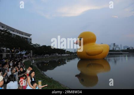 (140427) -- HO CHI MINH-VILLE, 27 avril (Xinhua) -- les gens observent le canard géant en caoutchouc dans le quartier résidentiel de Phu My Hung à Ho Chi Minh-ville (HCM), Vietnam, 26 avril 2014. Un canard en caoutchouc de 18 mètres de haut, qui a captivé les gens à travers le monde, sera exposé au lac Crescent dans le quartier résidentiel Phu My Hung de la ville de HCM du 27 avril au 31 mai, ont rapporté samedi les médias locaux. Conçu par l'artiste néerlandais Florentijn Hofman, le canard en caoutchouc a commencé une tournée intitulée Spreading Joys Around the World en 2007. HCM City sera le 16e lieu où il sera présenté. (Xinhua/Tao Jun) (dzl) VIETNAM- Banque D'Images