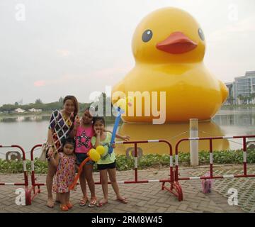 (140427) -- HO CHI MINH VILLE, 26 avril (Xinhua) -- des gens posent pour des photos avec le canard géant en caoutchouc dans le quartier résidentiel de Phu My Hung à Ho Chi Minh (HCM) ville, Vietnam, 26 avril 2014. Un canard en caoutchouc de 18 mètres de haut, qui a captivé les gens à travers le monde, sera exposé au lac Crescent dans le quartier résidentiel Phu My Hung de la ville de HCM du 27 avril au 31 mai, ont rapporté samedi les médias locaux. Conçu par l'artiste néerlandais Florentijn Hofman, le canard en caoutchouc a commencé une tournée intitulée Spreading Joys Around the World en 2007. HCM City sera le 16e lieu où il sera présenté. (Xinhua/Tao Jun) Banque D'Images