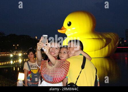 (140427) -- HO CHI MINH VILLE, 26 avril (Xinhua) -- des gens posent pour des photos avec le canard géant en caoutchouc dans le quartier résidentiel de Phu My Hung à Ho Chi Minh (HCM) ville, Vietnam, 26 avril 2014. Un canard en caoutchouc de 18 mètres de haut, qui a captivé les gens à travers le monde, sera exposé au lac Crescent dans le quartier résidentiel Phu My Hung de la ville de HCM du 27 avril au 31 mai, ont rapporté samedi les médias locaux. Conçu par l'artiste néerlandais Florentijn Hofman, le canard en caoutchouc a commencé une tournée intitulée Spreading Joys Around the World en 2007. HCM City sera le 16e lieu où il sera présenté. (Xinhua/Tao Jun) Banque D'Images