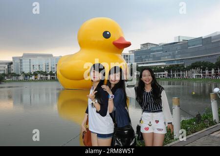 (140427) -- HO CHI MINH VILLE, 26 avril (Xinhua) -- des gens posent pour des photos avec le canard géant en caoutchouc dans le quartier résidentiel de Phu My Hung à Ho Chi Minh (HCM) ville, Vietnam, 26 avril 2014. Un canard en caoutchouc de 18 mètres de haut, qui a captivé les gens à travers le monde, sera exposé au lac Crescent dans le quartier résidentiel Phu My Hung de la ville de HCM du 27 avril au 31 mai, ont rapporté samedi les médias locaux. Conçu par l'artiste néerlandais Florentijn Hofman, le canard en caoutchouc a commencé une tournée intitulée Spreading Joys Around the World en 2007. HCM City sera le 16e lieu où il sera présenté. (Xinhua/Tao Jun) Banque D'Images