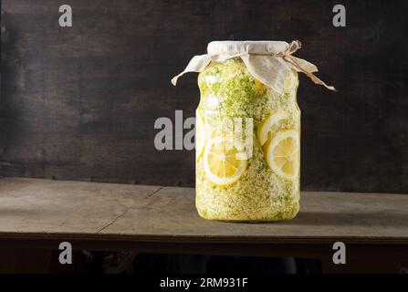 Les fleurs plus âgées boivent du verre de jus. Fleur blanche et citron. Boutons de récolte pour préparer du sirop et boire l'été. Cuisine et nourriture sur la table. Plante de Sambucus en pot. Banque D'Images