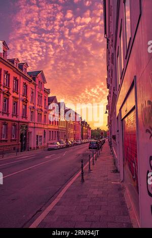 Coucher de soleil sur la rue en Allemagne avec des nuages de couleur chaude et rue presque vide Banque D'Images