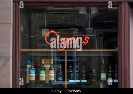 Une enseigne de cigares au néon et des bouteilles de whisky exposées dans une vitrine, Royaume-Uni Banque D'Images