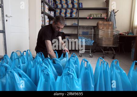 Un bénévole emballe de la nourriture pour les personnes dans le besoin au Centre d’accueil et de solidarité de la municipalité d’Athènes (KYADA) dans le centre-ville d’Athènes, Grèce, le 9 mai 2014. La crise de la dette en cours en Grèce a porté à 20 000 le nombre de personnes sollicitant l’aide de la KYADA, contre 3 000 avant la crise. (Xinhua photo/Marios Lolos) GRÈCE-ATHÈNES-CHARITÉ-BÉNÉVOLES-DISTRIBUTION ALIMENTAIRE PUBLICATIONxNOTxINxCHN un volontaire emballe de la nourriture pour les célébrités dans le besoin au Centre d'accueil et de solidarité de la municipalité d'Athènes dans le centre d'Athènes en Grèce LE 9 2014 mai la crise de la dette en cours dans GRE Banque D'Images