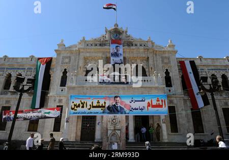 DAMAS, le 13 mai 2014 - des affiches de campagne électorale du président sortant Bachar al-Assad sont vues dans une gare de Damas, capitale de la Syrie, le 13 mai 2014. Des affiches et des banderoles représentant les trois candidats à la présidence de la Syrie décorent les rues principales de Damas, le président sortant Bachar al-Assad recevant, comme on pouvait s'y attendre, la part du lion de la publicité, alors que la campagne pour les élections débutera le 12 mai. La Cour constitutionnelle suprême de la Syrie a accepté la candidature de trois candidats, à savoir Maher Abdul-Hafiz Hajjar, Hassan Abdullah al-Nouri et Bachar al-Assad, pour la prés de juin 3 Banque D'Images