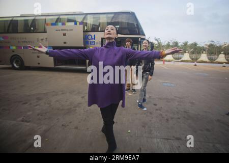 (140520) -- PÉKIN, 20 mai 2014 (Xinhua) -- Feng Ying, directeur du Ballet national de Chine, âgé de 52 ans, montre des routines pour les danseurs en attendant que leurs bagages soient chargés à l'aéroport Haikou Meilan de Haikou, dans la province de Hainan du sud de la Chine, le 11 janvier 2014. Avant de pouvoir présenter une performance parfaite sous les projecteurs, chaque membre du Ballet national de Chine doit suivre une formation sévère et ardue pendant des années. Pourtant, ils ont choisi de persévérer dans ce qu'ils aiment vraiment. Des années de labeur leur permettent non seulement une bonne forme corporelle, l'expertise et la disposition, mais leur offre également une vie longue g Banque D'Images