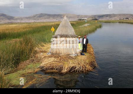 (140520) -- PUNO, 20 mai 2014 (Xinhua) -- des gens se tiennent à côté d'une maison sur l'île flottante Los Uros au lac Titicaca, dans la région de Puno, Pérou, le 13 mai 2014. Le lac Titicaca et ses îles flottantes dans la région de Puno au Pérou ont non seulement des attractions naturelles, mais aussi une culture unique en raison du peuple Quechua de Juliaca qui y vit. Le lac Titicaca est situé dans le plateau de Collao, avec les îles de Luna, Taquile, Amantani, Uros et Suriqui. (Xinhua/Luis Camacho)(zhf) PERU-PUNO-TITICACA LAKE-FLOATING ISLAND PUBLICATIONxNOTxINxCHN Puno Mai 20 2014 célébrités de XINHUA debout à côté d'une maison Banque D'Images