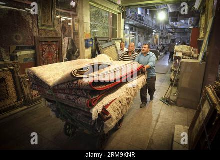 (140526) -- TÉHÉRAN, 26 mai 2014 (Xinhua) -- un iranien porte un tapis dans un bazar à tapis dans le centre-ville de Téhéran, Iran, le 26 mai 2014. Le marché international des exportations de tapis iraniens demeure stable, malgré une récession sur le marché intérieur. Environ un million de personnes sont impliquées dans l'industrie des tapis tissés à la main à travers le pays. (Xinhua/Ahmad Halabisaz) IRAN-TÉHÉRAN-INDUSTRIE DU TAPIS PUBLICATIONxNOTxINxCHN TÉHÉRAN Mai 26 2014 XINHUA à l'homme iranien porte un tapis dans un bazar de tapis au centre-ville DE TÉHÉRAN Iran en mai 26 2014 le marché international pour l'exportation de tapis en Iran S reste stable malgré un R. Banque D'Images