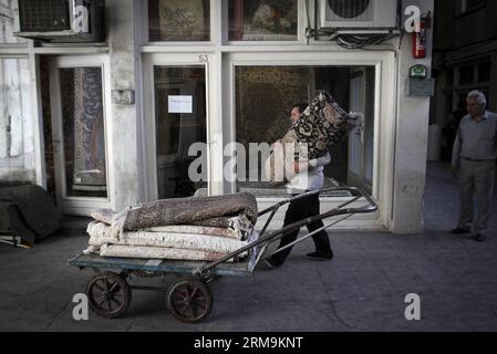 (140526) -- TÉHÉRAN, 26 mai 2014 (Xinhua) -- un iranien porte un tapis dans un bazar à tapis dans le centre-ville de Téhéran, Iran, le 26 mai 2014. Le marché international des exportations de tapis iraniens demeure stable, malgré une récession sur le marché intérieur. Environ un million de personnes sont impliquées dans l'industrie des tapis tissés à la main à travers le pays. (Xinhua/Ahmad Halabisaz) IRAN-TÉHÉRAN-INDUSTRIE DU TAPIS PUBLICATIONxNOTxINxCHN TÉHÉRAN Mai 26 2014 XINHUA à l'homme iranien porte un tapis dans un bazar de tapis au centre-ville DE TÉHÉRAN Iran en mai 26 2014 le marché international pour l'exportation de tapis en Iran S reste stable malgré un R. Banque D'Images