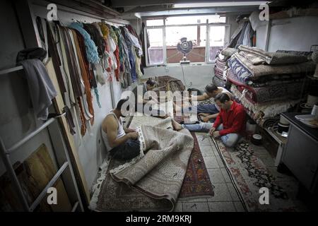 (140526) -- TÉHÉRAN, 26 mai 2014 (Xinhua) -- des travailleurs iraniens réparent un tapis dans un bazar à tapis dans le centre-ville de Téhéran, Iran, le 26 mai 2014. Le marché international des exportations de tapis iraniens demeure stable, malgré une récession sur le marché intérieur. Environ un million de personnes sont impliquées dans l'industrie des tapis tissés à la main à travers le pays. (Xinhua/Ahmad Halabisaz) IRAN-TÉHÉRAN-INDUSTRIE DU TAPIS PUBLICATIONxNOTxINxCHN TÉHÉRAN Mai 26 2014 XINHUA travailleurs iraniens MEND un tapis dans un bazar de tapis dans le centre-ville de TÉHÉRAN Iran EN mai 26 2014 le marché international pour l'exportation de tapis de l'Iran S reste stable malgré un Reces Banque D'Images