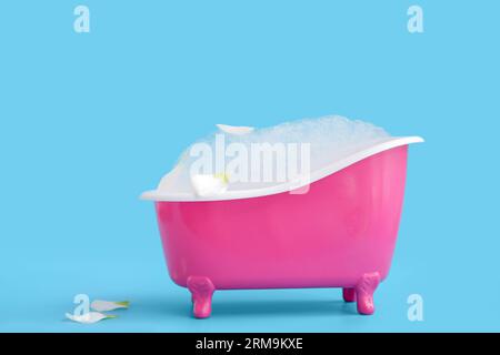 Petite baignoire avec mousse de savon et pétales de fleurs sur fond de couleur Banque D'Images