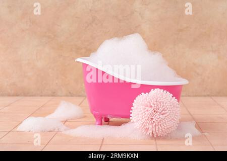 Petite baignoire avec mousse et éponge sur fond de couleur Banque D'Images