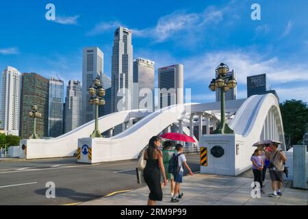 Piétons marchant à travers Elgin Bridge enjambant la rivière Singapour, Singapour, les gratte-ciel du quartier des affaires en arrière-plan Banque D'Images