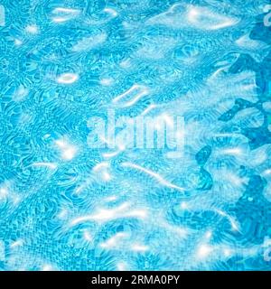 Eau dans la piscine. Fond de surface de l'eau avec des reflets de soleil et des ondulations Banque D'Images