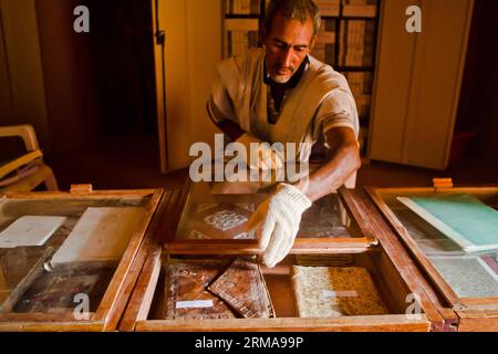 Abdullah expose des livres arabes anciens dans sa bibliothèque privée à Chinguetti, une ancienne ville de la région d'Adrar, Mauritanie, le 23 juin 2014. Sa bibliothèque Habott est la plus grande des cinq bibliothèques locales qui contiennent plus de 1 400 collections de livres anciens de la science de l'écriture à la main et différentes écritures du Coran. (Xinhua/Li Jing)(lyi) MAURITANIE-ADRAR-CHINGUETTI-VIE QUOTIDIENNE PUBLICATIONxNOTxINxCHN Abdullah expose des livres arabes anciens dans sa bibliothèque privée dans la ville antique de la région d'Adrar Mauritanie juin 23 2014 sa bibliothèque EST la plus grande des cinq bibliothèques locales avec plus de 1 400 Col Banque D'Images