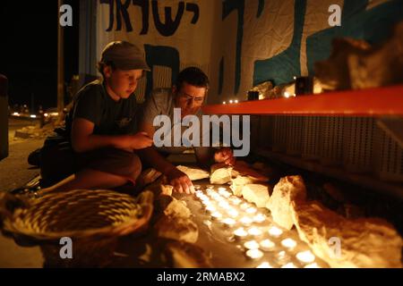 (140701) -- JÉRUSALEM, 30 juin 2014 (Xinhua) -- des Juifs allument des bougies à l'endroit où les trois adolescents israéliens ont disparu en Cisjordanie, le 30 juin 2014. Les forces de sécurité israéliennes ont découvert lundi soir les corps de trois adolescents israéliens portés disparus le 12 juin, près de Hébron en Cisjordanie, ont confirmé les militaires. Les corps d'Eyal Yifrach, de Naftali Frankel et de Gilad Shaer, 19 ans, tous deux âgés de 16 ans, ont été retrouvés dans les collines de Judée, dans le sud de la Cisjordanie, au nord d'Hébron, entre les villes palestiniennes de Beit Ummar et Halhul. Leurs corps ont été découverts dans une zone controlle Banque D'Images