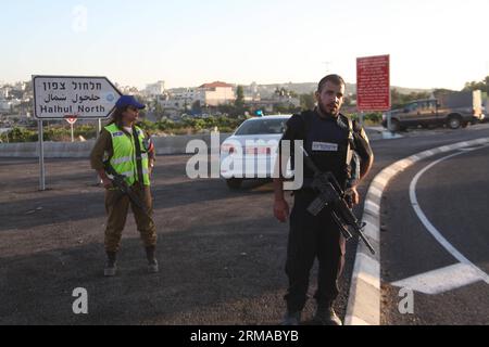 (140701) -- HÉBRON, 30 juin 2014 (Xinhua) -- des membres des forces de sécurité israéliennes se tiennent à côté de leurs véhicules alors qu'ils bloquent l'entrée nord du village de Halhul, près de la ville d'Hébron en Cisjordanie, le 30 juin 2014. Lundi, les corps des trois Israéliens enlevés il y a plus de deux semaines ont été découverts par les forces de sécurité juste au nord d'Hébron. Et après la découverte des trois corps israéliens, l'armée israélienne a bloqué toutes les entrées d'Hébron. (Xinhua/Mamoun Wazwaz) MIDEAST-HEBRON-MILITARY PUBLICATIONxNOTxINxCHN Hebron juin 30 2014 XINHUA membres d'Israe Banque D'Images