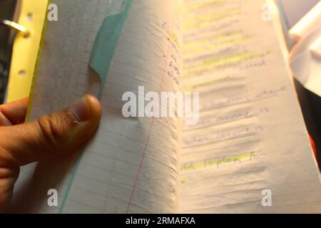 Photo de la main d'un élève qui défile dans un classeur de notes papier. Banque D'Images
