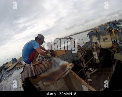 (140717) -- MANILLE, 17 juillet 2014 (Xinhua) -- Un homme répare le toit de sa maison après qu'il a été endommagé par le typhon Rammasun dans un bidonville de Manille, aux Philippines, le 17 juillet 2014. Le nombre de morts du typhon Rammasun est passé à 38, a déclaré jeudi l'agence locale de lutte contre les catastrophes. Le National Disaster Risk Reduction and Management Council (NDRRMC) a déclaré que le typhon avait également fait 10 blessés et que huit autres avaient été déclarés disparus. (Xinhua/Rouelle Umali) PHILIPPINES-MANILLE-TYPHON RAMMASUN-AFTERMATH PUBLICATIONxNOTxINxCHN Manille juillet 17 2014 XINHUA un homme RÉPARE le toit de sa maison après quoi d Banque D'Images