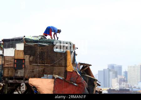 (140717) -- MANILLE, 17 juillet 2014 (Xinhua) -- Un homme répare le toit de sa maison après qu'il a été endommagé par le typhon Rammasun dans un bidonville de Manille, aux Philippines, le 17 juillet 2014. Le nombre de morts du typhon Rammasun est passé à 38, a déclaré jeudi l'agence locale de lutte contre les catastrophes. Le National Disaster Risk Reduction and Management Council (NDRRMC) a déclaré que le typhon avait également fait 10 blessés et que huit autres avaient été déclarés disparus. (Xinhua/Rouelle Umali) PHILIPPINES-MANILLE-TYPHON RAMMASUN-AFTERMATH PUBLICATIONxNOTxINxCHN Manille juillet 17 2014 XINHUA un homme RÉPARE le toit de sa maison après quoi d Banque D'Images