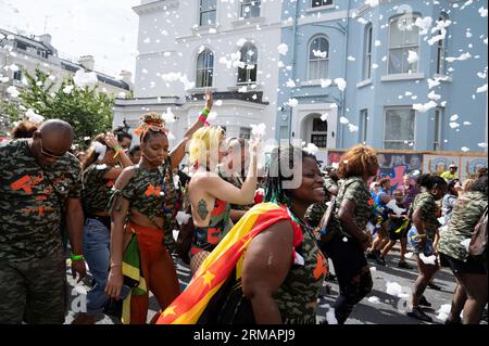 Le 27 août 2023, des centaines de milliers de fêtards célèbrent le premier jour du Carnaval à Notting Hill, West London, Angleterre en lançant du p coloré Banque D'Images