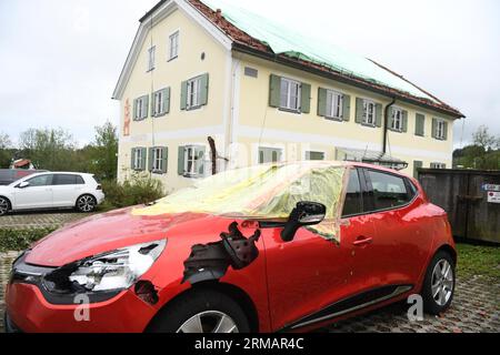 Bad Bayersoien, Allemagne. 27 août 2023. Après la tempête dans le quartier de Garmisch-Partenkirchen, le toit d'un immeuble résidentiel est provisoirement recouvert de bâches ; devant lui se trouve une voiture endommagée par la tempête. En raison de graves dégâts causés par la tempête, le bureau de district de Garmisch-Partenkirchen a déclaré dimanche une situation catastrophique pour la ville, qui compte environ 1 300 habitants. 80 % des bâtiments de la ville seraient gravement endommagés. Crédit : Felix Hörhager/dpa/Alamy Live News Banque D'Images